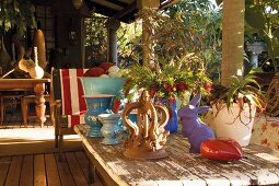 Sunny wooden terrace with vintage table, flowers and colorful decorative objects