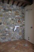 Shower head with running water in floor-level shower with stone wall