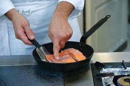 A chef frying salmon fillets