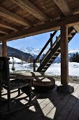 Seating area on terrace of wooden hut in snowy mountain landscape