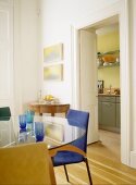 Blaue Trinkgläser auf Glastisch und Blick durch offene Tür in Küche