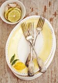 Ovale Teller, Gabel und Schälchen mit Zitrone und Knoblauch