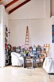 Workspace in niche of living room in front of half-height bookshelves and easel