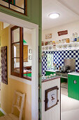 View into open-plan, colourful kitchen with partition wall separating hallway