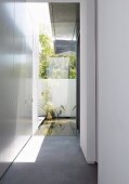 Narrow courtyard at side entrance of contemporary house with view of pool in garden
