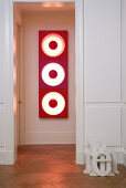 Wood-panelled doorway leading to hall with view of red 70s light sculpture