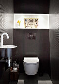 Tiled designer bathroom with chrome wash basin and picture with butterfly motif on broad light strip