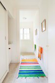 Bright, striped runner on floor of white corridor