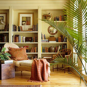 Chaise longue in front of fitted shelving in traditional interior