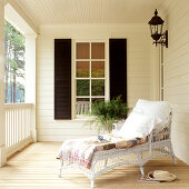 White wicker couch on veranda of traditional country house