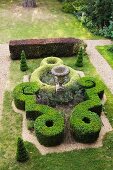 Garden design in style of castle grounds with antique amphora amongst artistic topiary box hedges