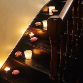 Lit candle lanterns and roses on old, dark wood staircase treads