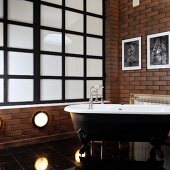 Badezimmer im Vintagestil mit freistehender Badewanne vor Wand mit Ziegellook