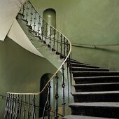 Vintage Treppenhaus - Schmiedeeisernes Metallgeländer an wendelnder Treppe und grün grau getönte Wände mit kleinen Nischen