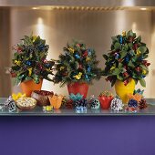 Small Christmas tree arrangements with brightly wrapped sweeties and colourful fir cones