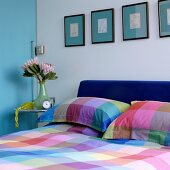 Cheerful colour scheme in bedroom with checked bed linen below pictures on turquoise mounts combined with light blue sliding door