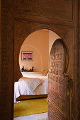 Offene Zimmertür mit Spitzbogen in marokkanischem Stil und Blick ins Schlafzimmer