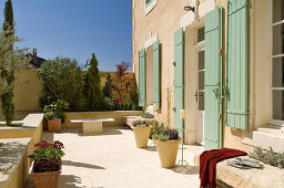 Sonnige Terrasse mit Pflanzentöpfen vor mediterranem Wohnhaus