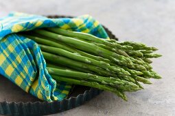 Green Thai asparagus wrapped in a napkin on a baking tray