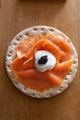 A cracker topped with smoked salmon, sour cream and caviar