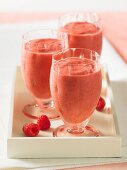 Three raspberry and cranberry smoothies on a tray