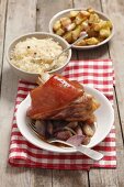 Pork knuckle with shallots, roast potatoes and sauerkraut