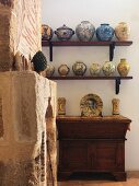 Old, stone fireplace and hand-made vases on shelves above antique cabinet