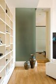 Corner of modern living room - Chinese vases against glass wall next to doorway and modern, white fitted shelving