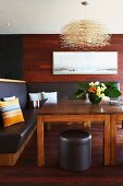 Corner bench upholstered in black leather and wooden table in dining room with wood-panelled walls and wooden floor