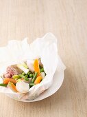Andouillette with spring vegetables in parchment paper