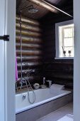 Modern bathroom in log cabin - sunken bathtub against log walls