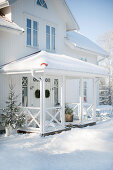Weisses Holzhaus mit überdachtem Eingang in Winterstimmung