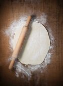 Pizza dough with a rolling pin (view from above)