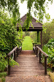 Wooden bridge and small wooden pavilion in park-like gardens