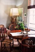 English chairs and round table in a living room in front of an abstract painting and side table with a modern lamp