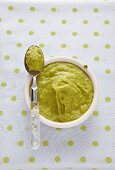 Baby food with peas in a little dish on a polka dot table cloth