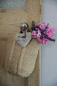 Knitted bag with posy and fabric heart hanging on door knob