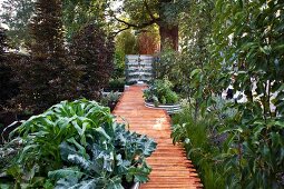 Garden path made from recycled building timer leading to pond with water tank in background