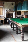 Pendant lamps with pleated fabric lampshades above snooker table in rustic interior