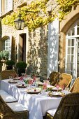 Festively set table on sunny terrace next to Mediterranean country house