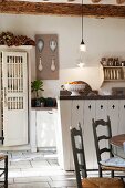 Wooden chairs, counter and cupboard with turned spindle doors in rustic kitchen