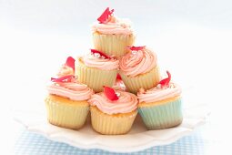 A stack of cupcakes topped with pink frosting on a plate