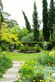 Colourful planters next to pond in front of cypress trees in Mediterranean garden