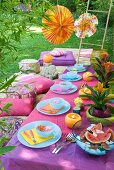 Orientalisches Gelage im Garten mit pastellblauem Geschirr zu Tischdecken und Sitzkissen in Violetttönen