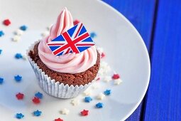 A chocolate cupcake topped with pink cream and a Union Jack