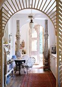 Ausgefallene Küche im Stilmix mit Vintageherd, Eisentisch und -stühlen und dekorativen Säulen