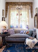 Style mix in a small living space - blue tones with a classic sofa and heavy iron table in front of a large window with an eye catching pelmet