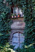 Ivy covered facade of a traditional country home with decoratively carved windows