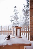 Eingeschneiter Tisch mit Laterne auf Terrasse