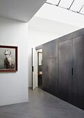 Installation with metal-effect wall in minimalist interior with skylight